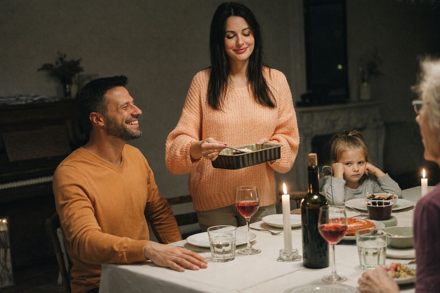 En glad familie samlet til aftensmad med RetNemt måltidskasse ved et oplyst bord.